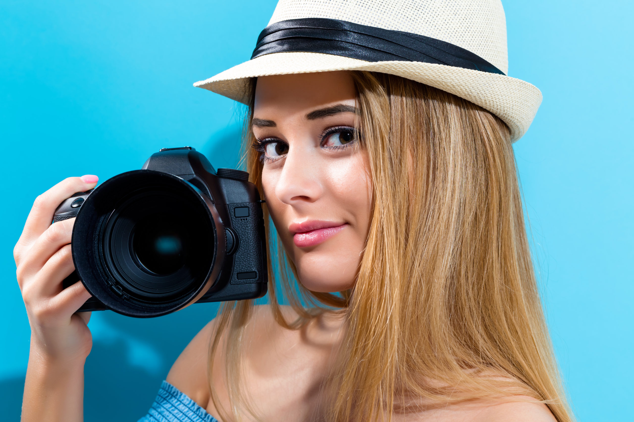 Young woman holding a camera on a blue background